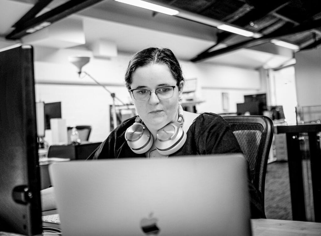 working woman with glasses and headset infront of her laptop